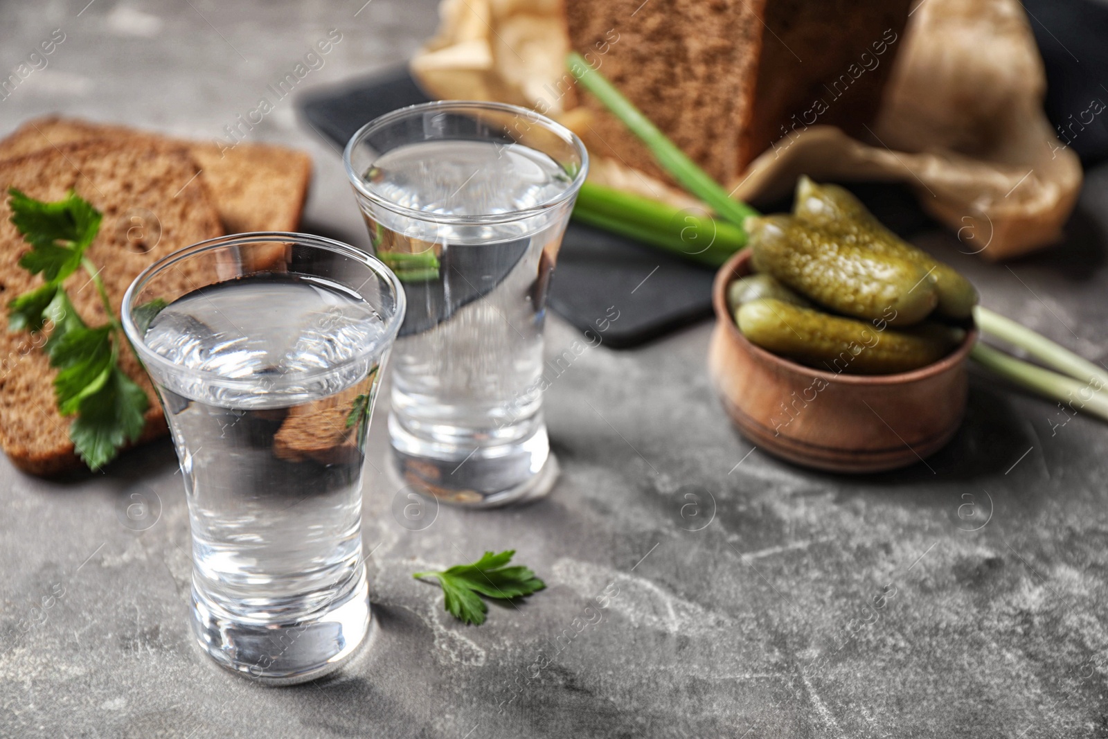 Photo of Cold Russian vodka with snacks on grey table, closeup