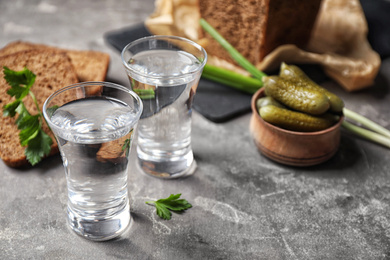 Photo of Cold Russian vodka with snacks on grey table, closeup