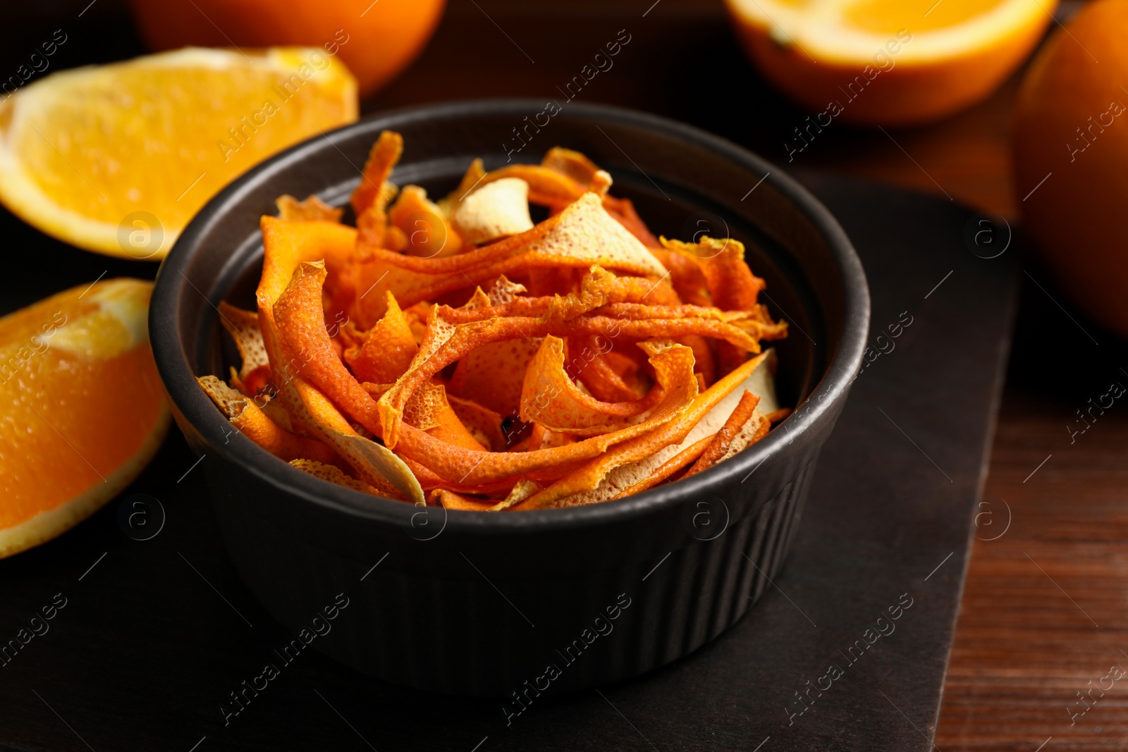 Photo of Bowl with dry orange peels and fresh fruits on wooden table, closeup