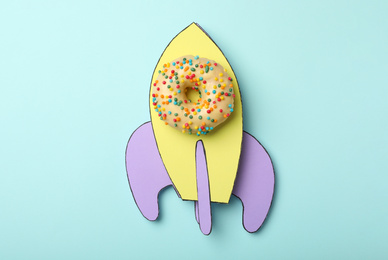 Photo of Rocket made with donut and paper on light blue background, top view