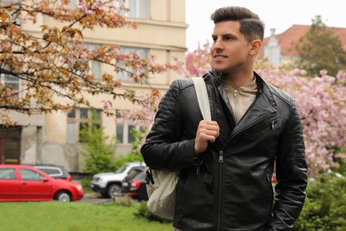 Tourist with stylish backpack walking on city street