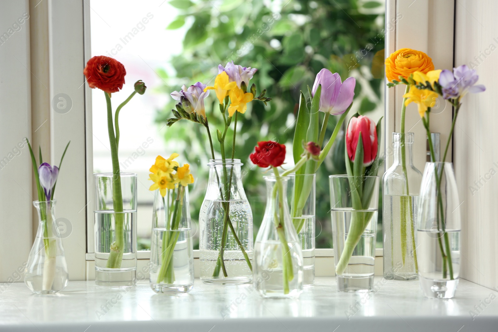 Photo of Beautiful spring flowers in glassware on window sill