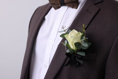 Photo of Handsome young groom with boutonniere on light grey background. Wedding accessory