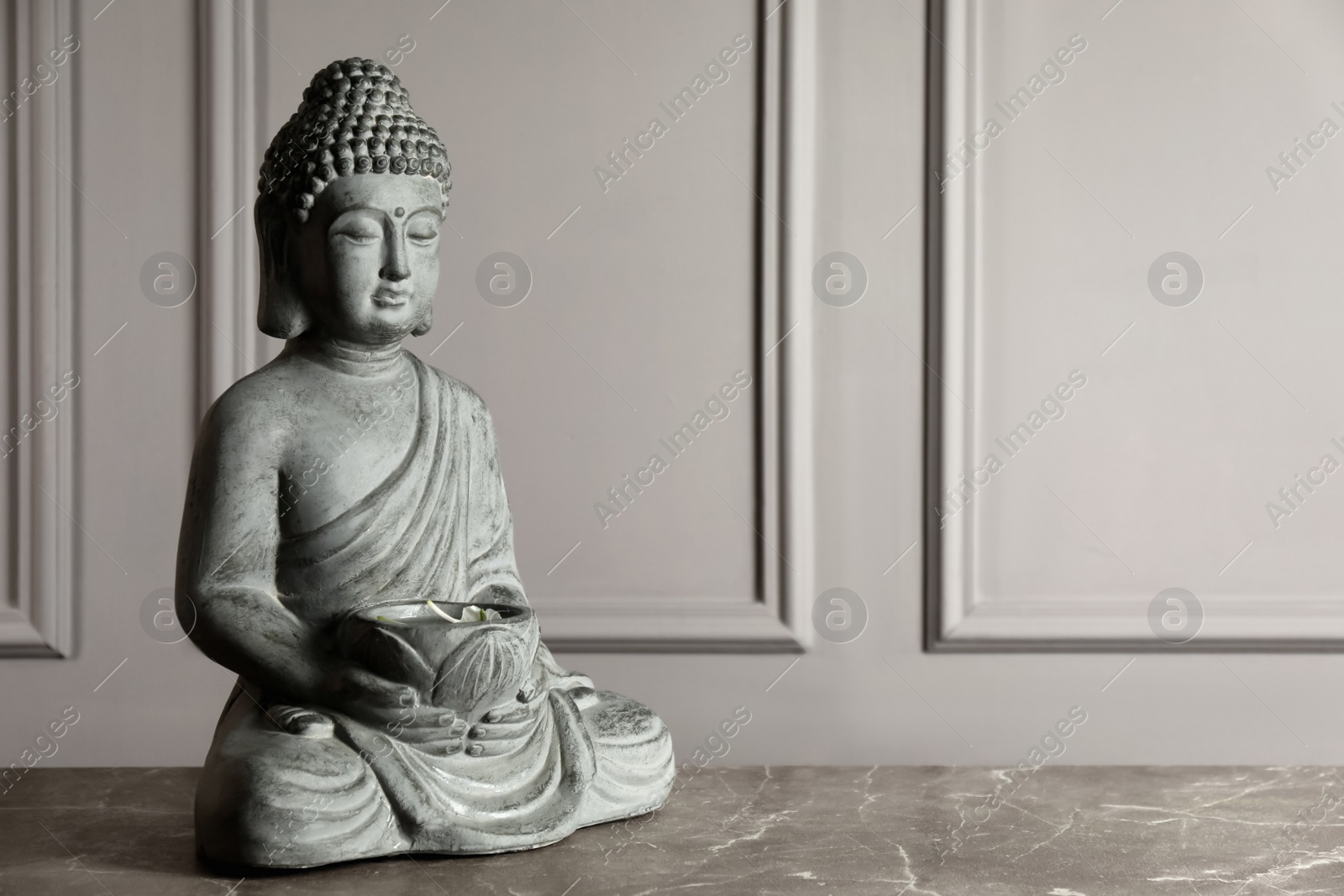 Photo of Buddha statue on grey table. Space for text