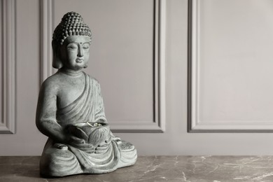 Photo of Buddha statue on grey table. Space for text