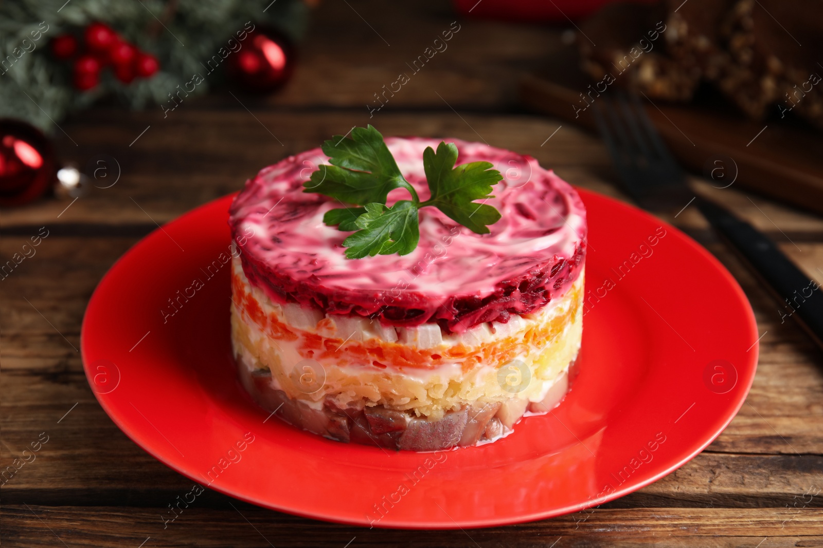 Photo of Herring under fur coat served on wooden table, closeup. Traditional russian salad