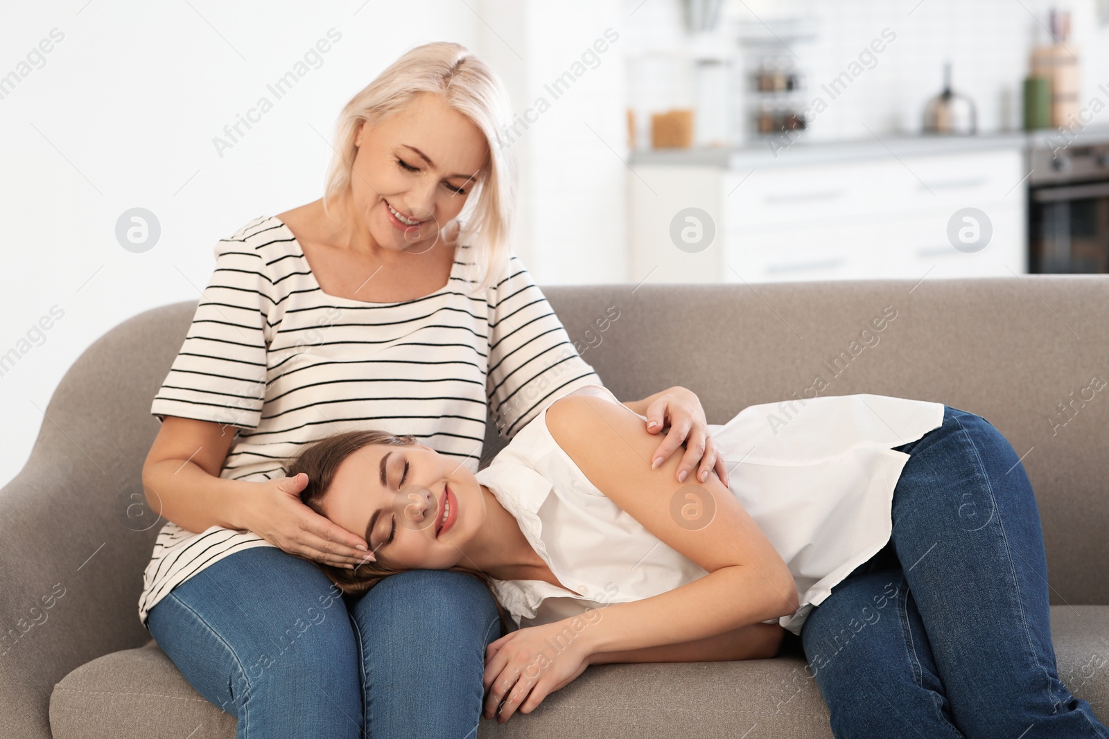 Photo of Young woman lying on her mother's lap at home