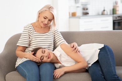 Young woman lying on her mother's lap at home