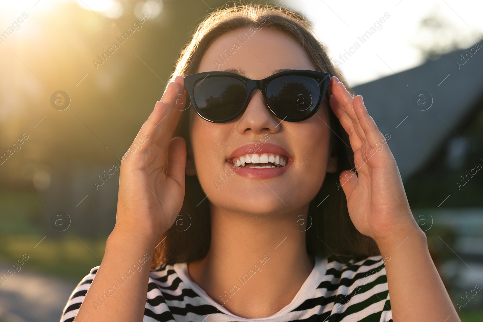 Photo of Beautiful smiling woman in sunglasses outdoors on sunny day