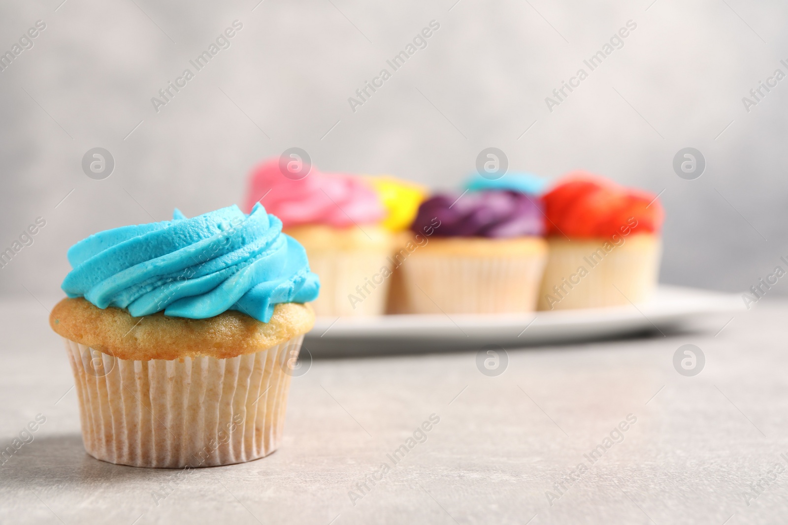 Photo of Delicious cupcakes with bright cream on gray table, selective focus