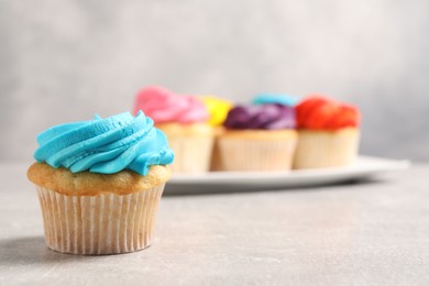 Photo of Delicious cupcakes with bright cream on gray table, selective focus