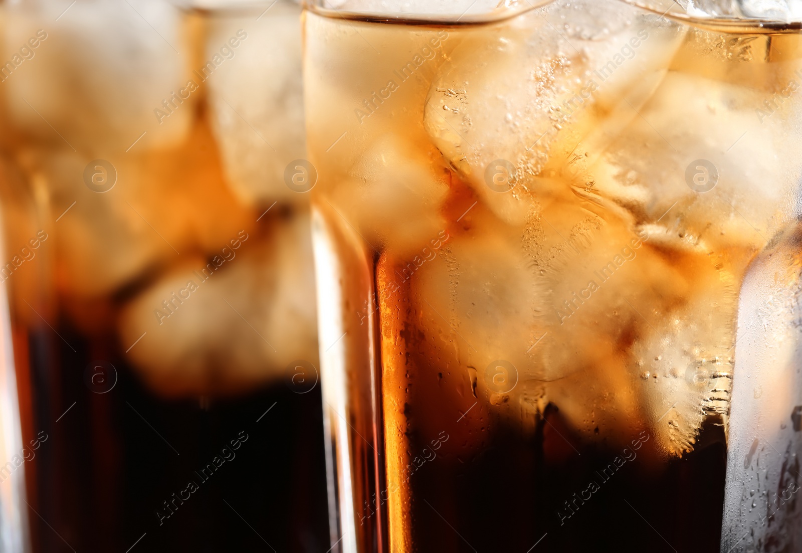 Photo of Glass of tasty refreshing cola with ice cubes on blurred background, closeup. Space for text