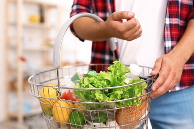 Photo of Man with shopping basket full of products in grocery store, closeup