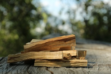 Palo santo sticks on wooden table outdoors, closeup