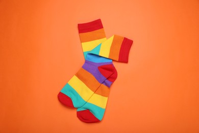 Photo of Rainbow socks on orange background, top view. LGBT pride
