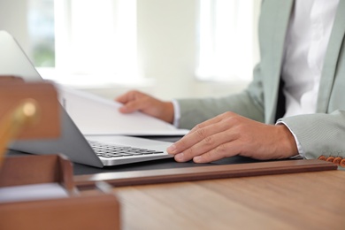Photo of Male notary working with laptop at table in office, closeup