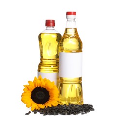 Photo of Bottles of sunflower cooking oil, seeds and yellow flower on white background