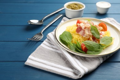 Photo of Tasty spaghetti squash with bacon and basil served on blue wooden table, space for text