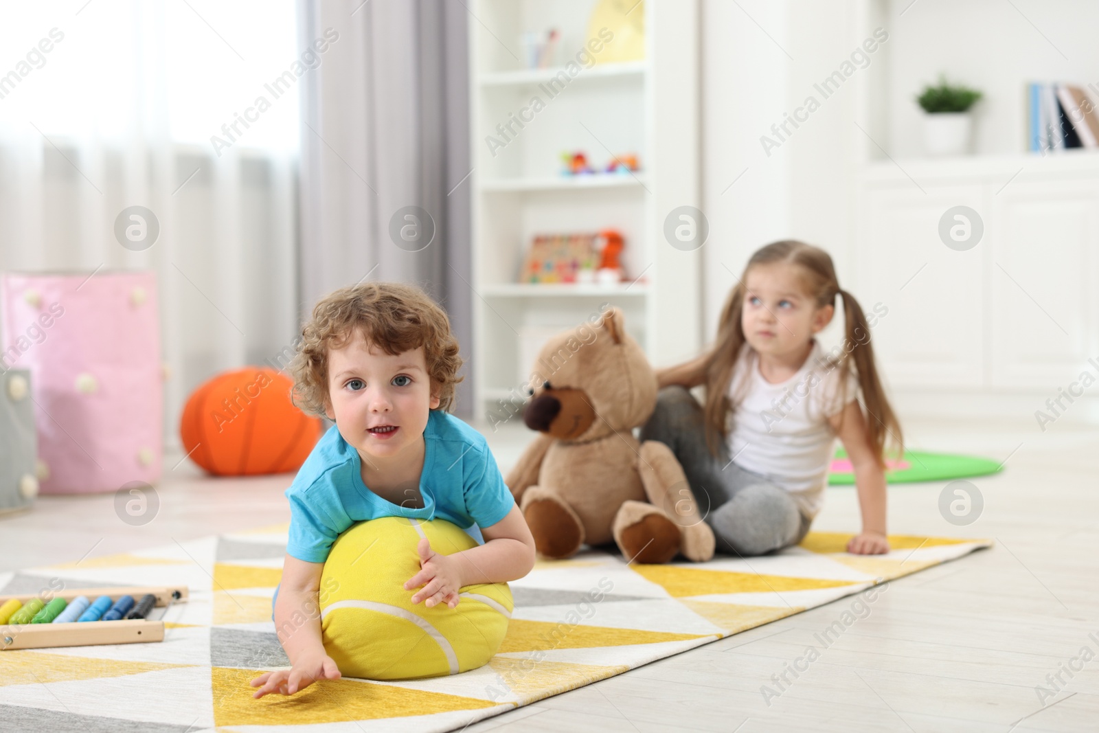 Photo of Cute little children playing together on floor in kindergarten