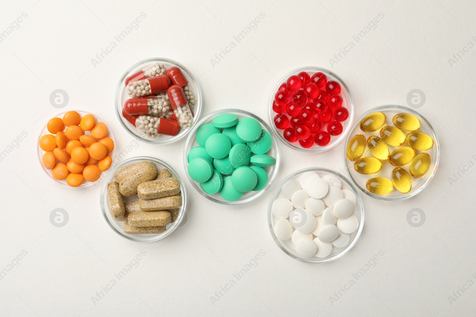 Photo of Different dietary supplements in bowls on white background, flat lay