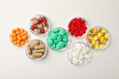 Photo of Different dietary supplements in bowls on white background, flat lay