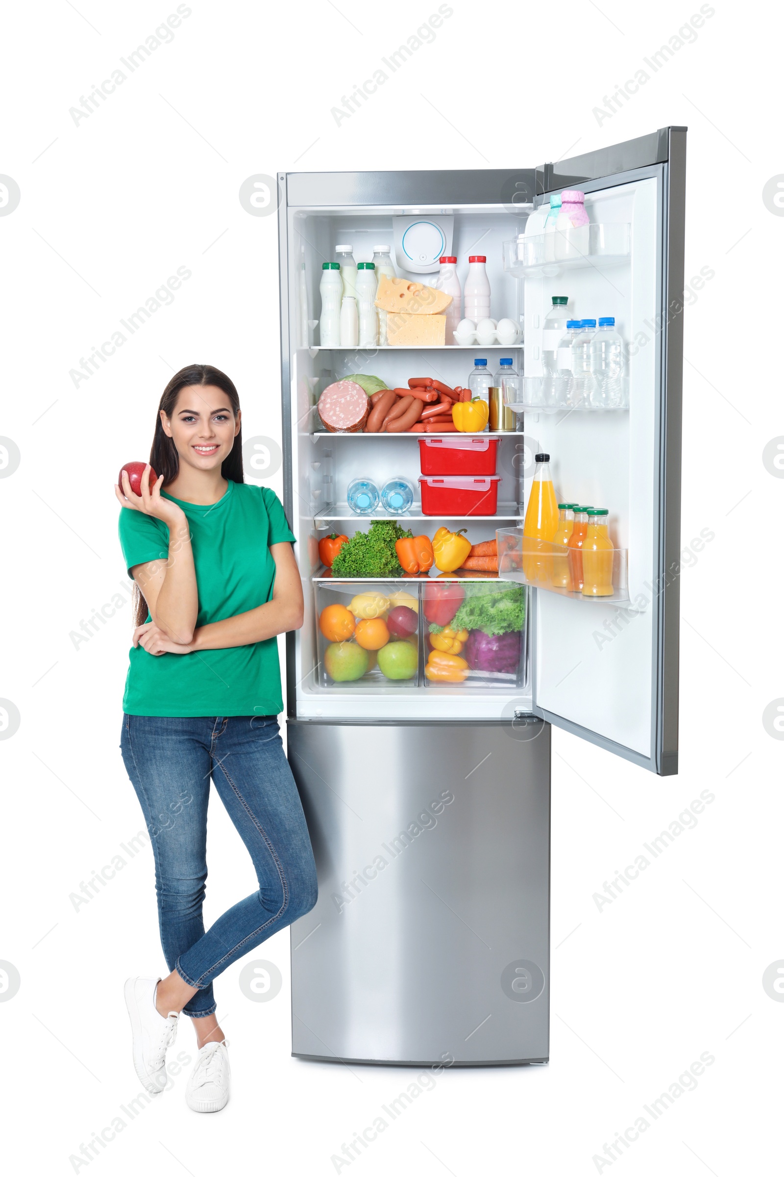 Photo of Young woman with apple near open refrigerator on white background