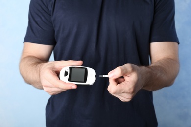 Man holding glucometer on color background. Diabetes test