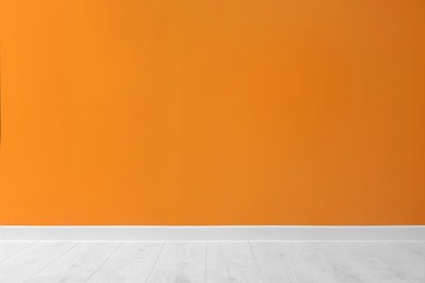 Photo of Beautiful orange wall and wooden floor in clean empty room
