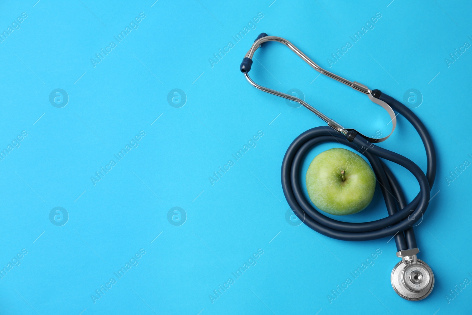 Photo of Stethoscope and apple on color background, top view. Medical equipment