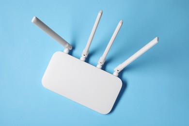 Photo of New white Wi-Fi router on light blue background, top view