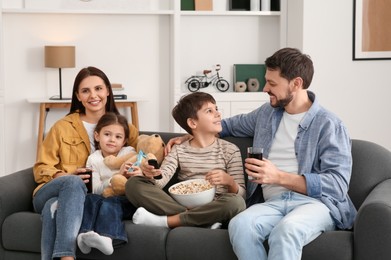 Photo of Family spending time together on sofa at home. Son changing TV channels with remote control