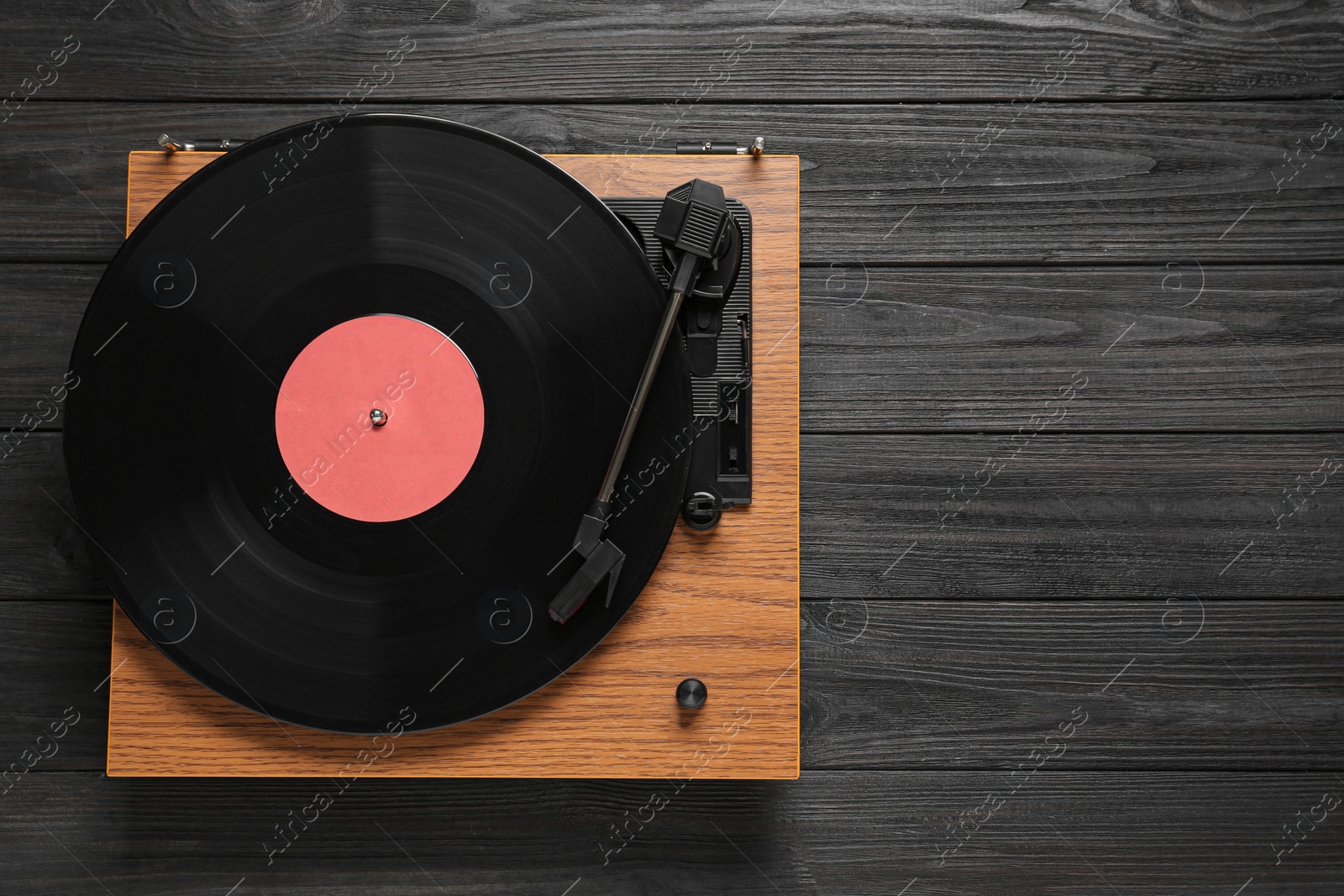 Photo of Turntable with vinyl record on black wooden background, top view. Space for text
