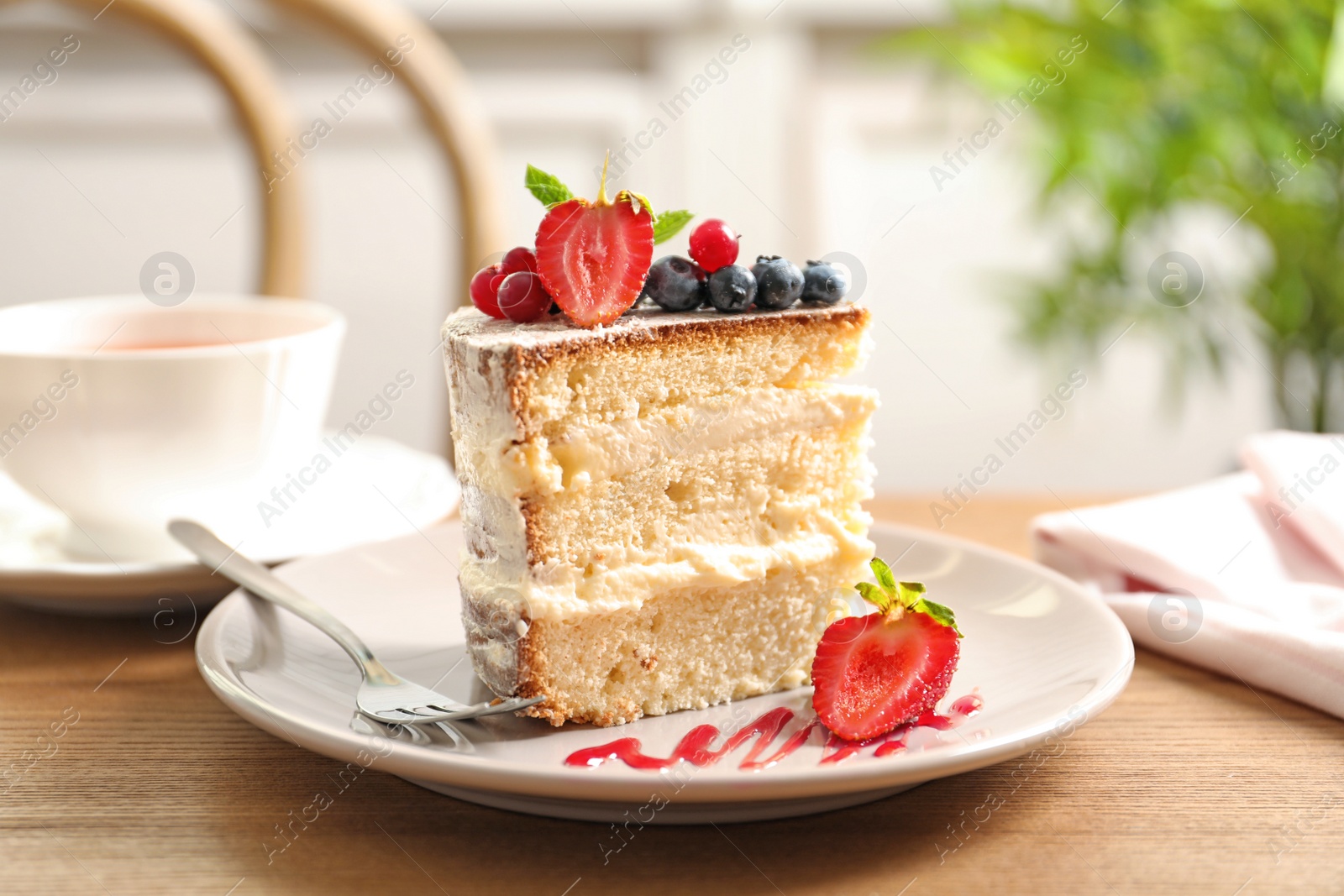 Photo of Piece of delicious homemade cake with fresh berries served on wooden table