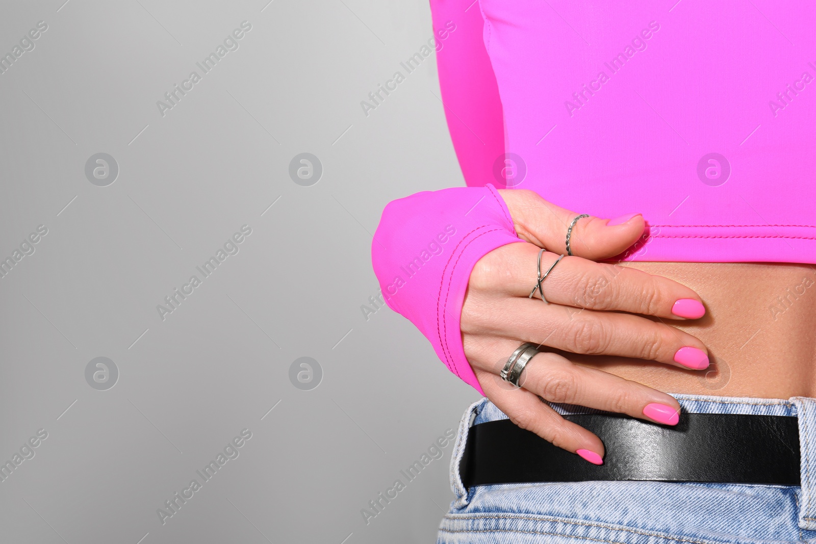 Photo of Woman showing manicured hand with pink nail polish on grey background, closeup. Space for text