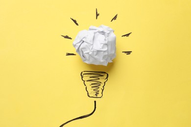 Photo of Idea concept. Light bulb made with crumpled paper and drawing on yellow background, top view