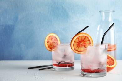 Composition with orange drink and ice cubes in glasses on table. Space for text