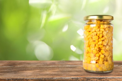 Image of Jar of pickled corn on wooden table against blurred background, space for text