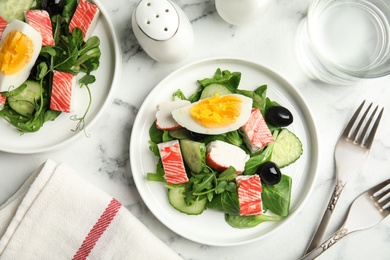 Photo of Delicious crab stick salad served on white marble table, flat lay