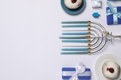 Flat lay composition with Hanukkah menorah and donuts on white background, space for text