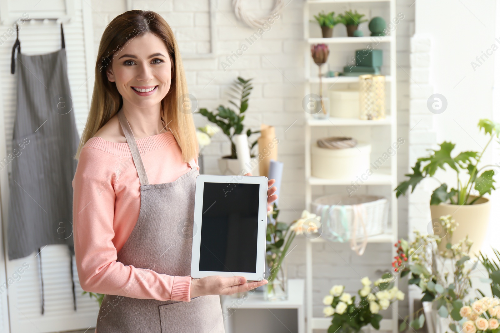 Photo of Female florist holding tablet at workplace