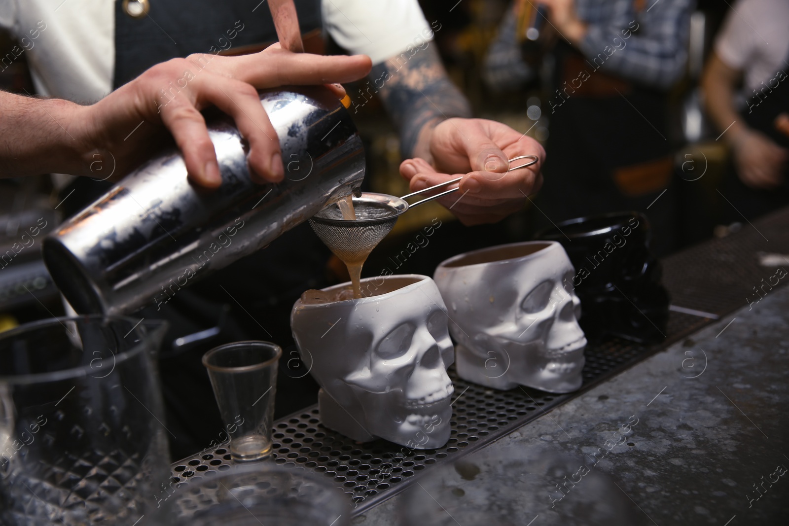 Photo of Bartender pouring tasty cocktail at counter in nightclub, closeup