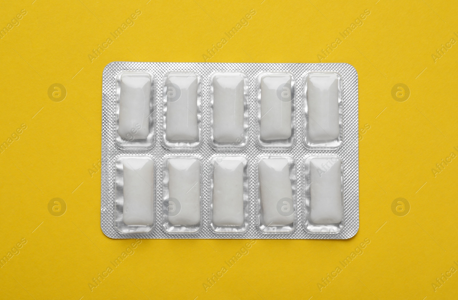 Photo of Blister of tasty chewing gums on yellow background, top view