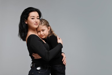 Photo of Beautiful mother hugging with little daughter on grey background. Space for text