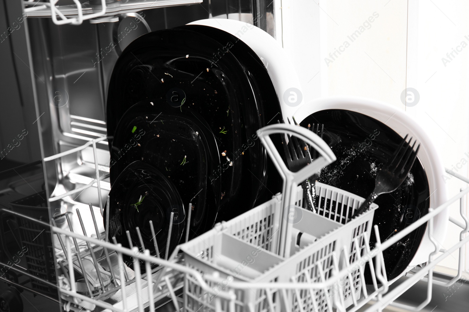 Photo of Open dishwasher with dirty tableware in kitchen, closeup