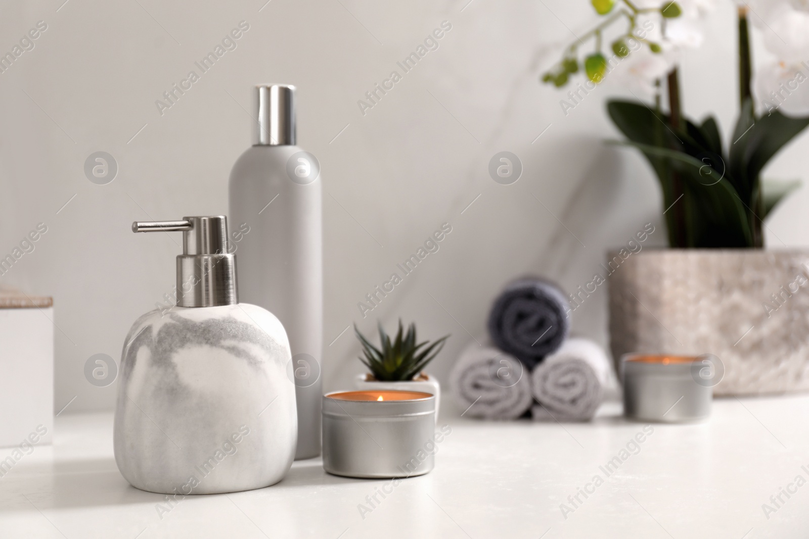 Photo of Toiletries and burning candle on countertop in bathroom. Space for text