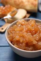 Photo of Bowl with delicious apple jam on blue wooden table, closeup