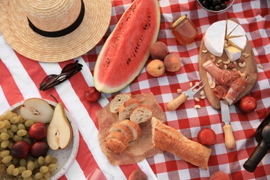 Different tasty snacks on picnic blanket, flat lay