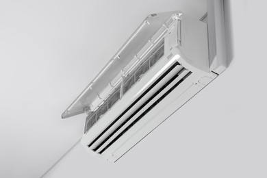 Modern air conditioner on white wall indoors