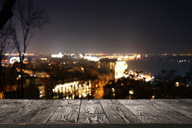 Image of Empty wooden surface and blurred view of modern night city. Bokeh effect 