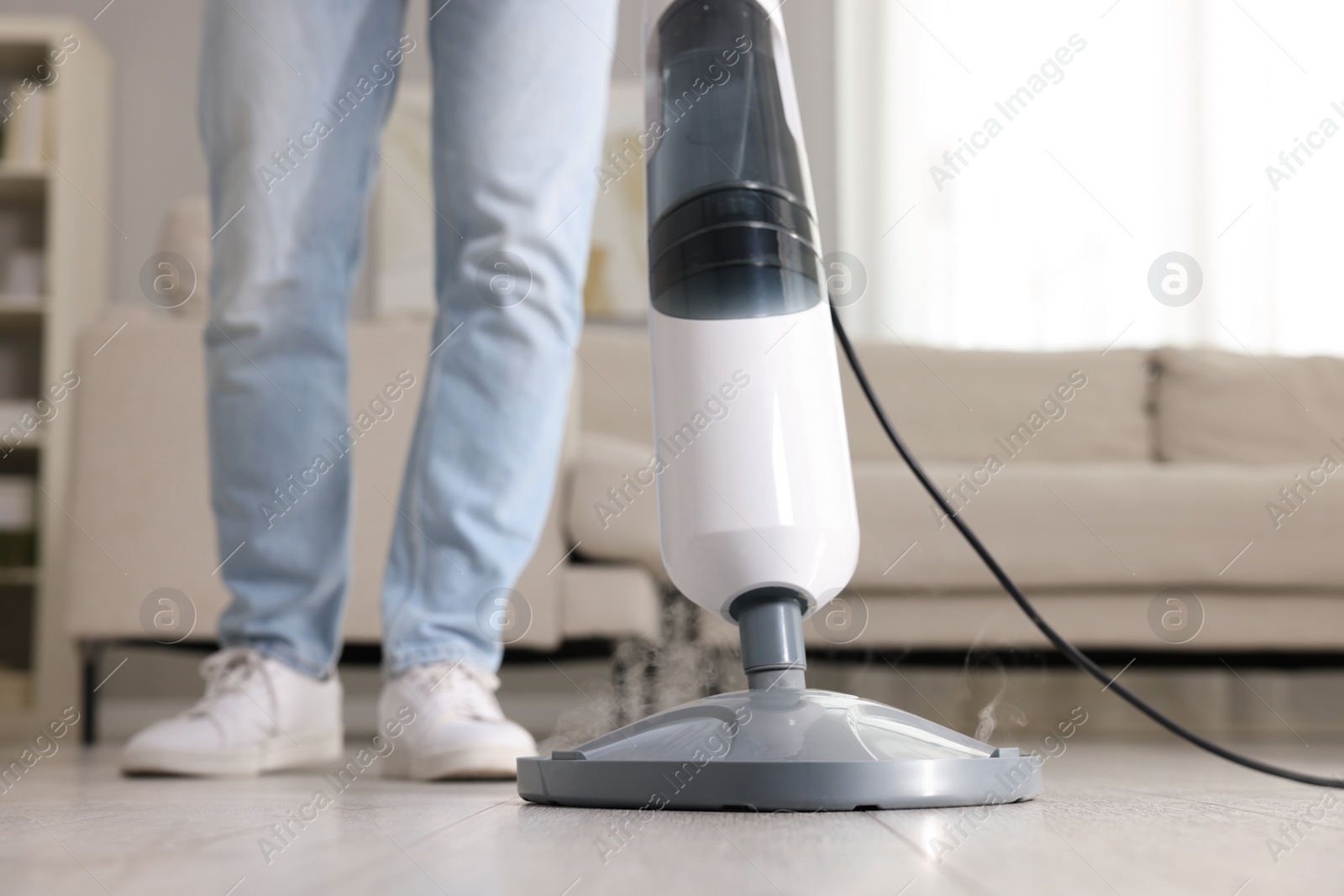 Photo of Man cleaning floor with steam mop at home, closeup